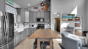 Una cocina moderna con armarios grises, electrodomésticos de acero inoxidable y una mesa de comedor de madera.