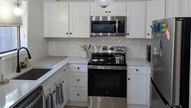 A modern kitchen with white cabinets, stainless steel appliances, a black oven, and a microwave. - Beautiful 3/2 Home, quiet location, close proximity to Texas A&M University (Bryan)