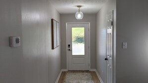 A hallway with a wooden floor, white walls, a door with frosted glass, and a ceiling light fixture. - Beautiful 3/2 Home, quiet location, close proximity to Texas A&M University (Bryan)