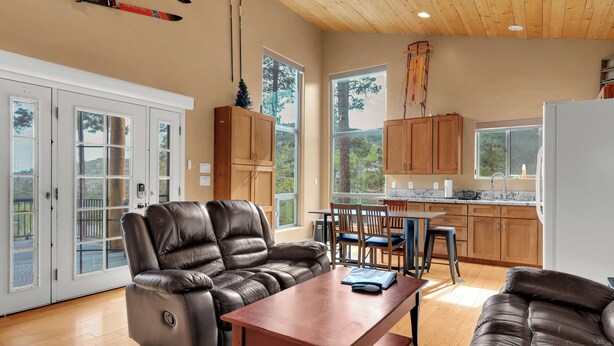 A spacious living area with a leather sofa, a wooden table, and a kitchen in the background. - Ski Tucson Cabin at Mt Lemmon Hotel Overlooking Summerhaven, Arizona (Mount Lemmon)