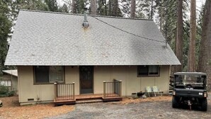 A single-story house with a sloped roof, a front porch, and a driveway. - GREAT FAMILY LOCATION!  Peace in the Trees N Mace (Pioneer)