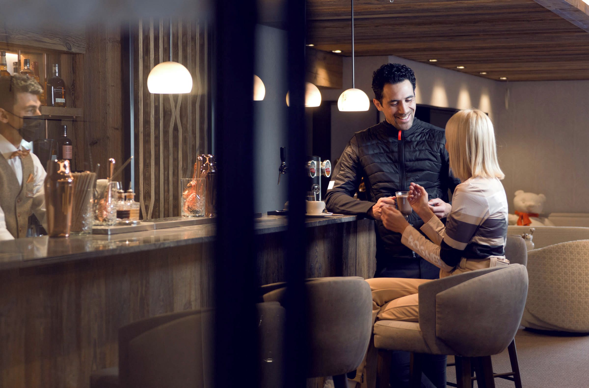 A bar area with a counter, bar stools, and a person serving drinks.