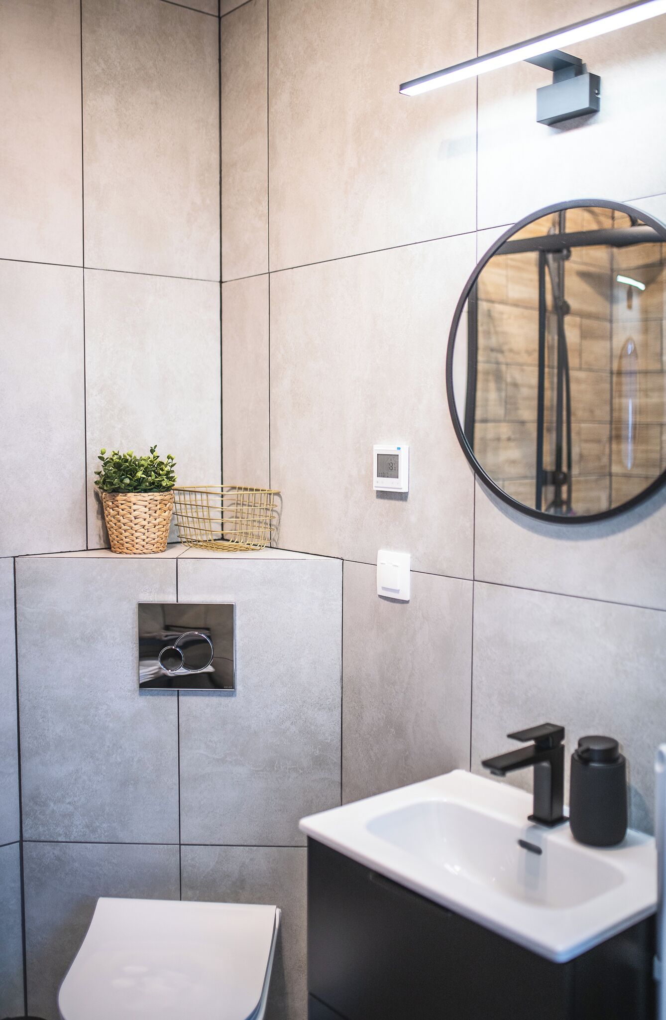 Une salle de bain moderne avec un grand miroir, un lavabo et un espace douche.