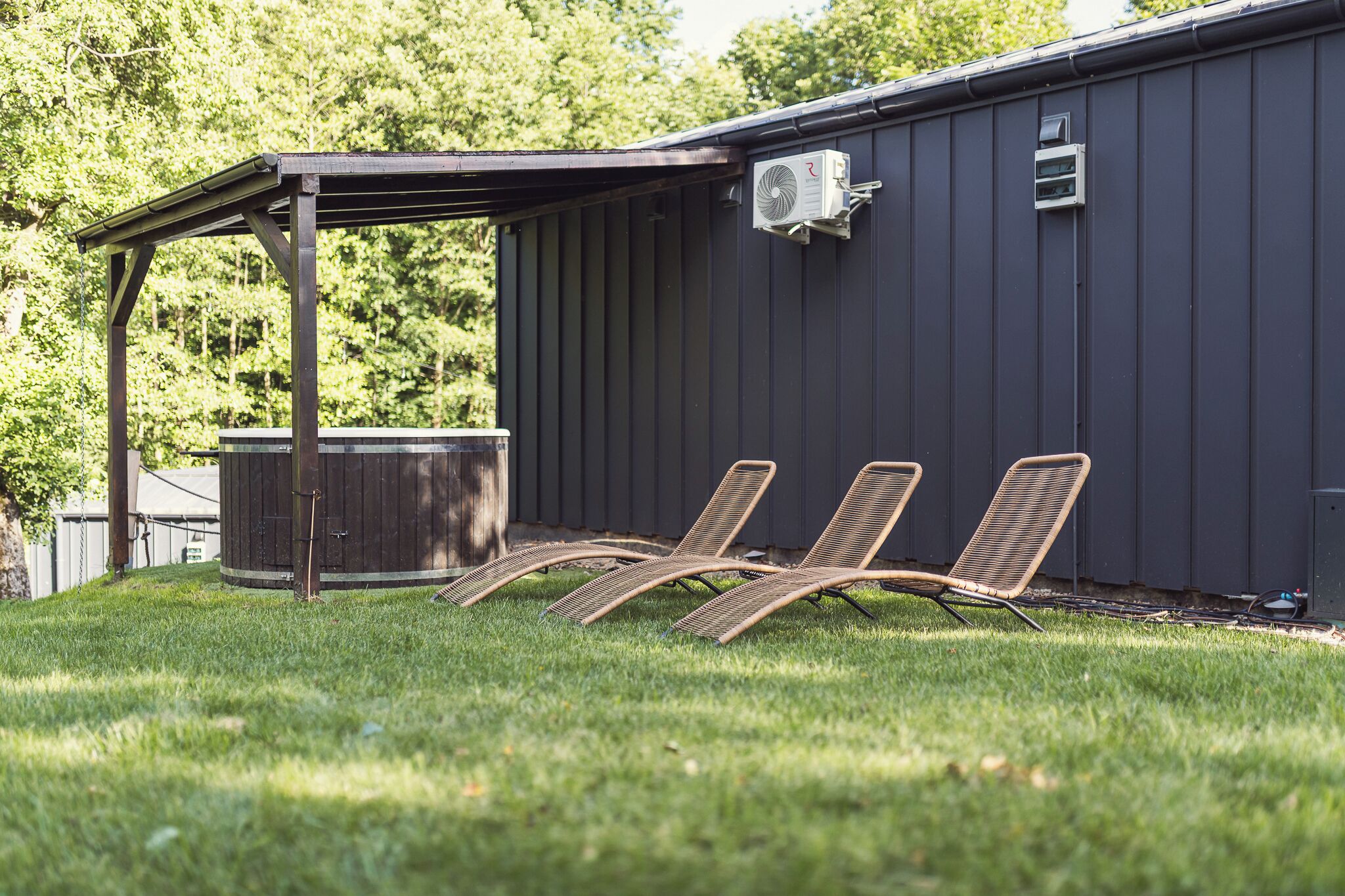 A covered patio area with a pool, outdoor chairs, and a water heater attached to a building.