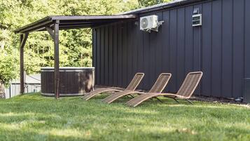 A covered patio area with a pool, outdoor chairs, and a water heater attached to a building.