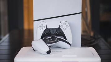 Um console PlayStation 5 sobre um suporte branco com um controle de jogo.