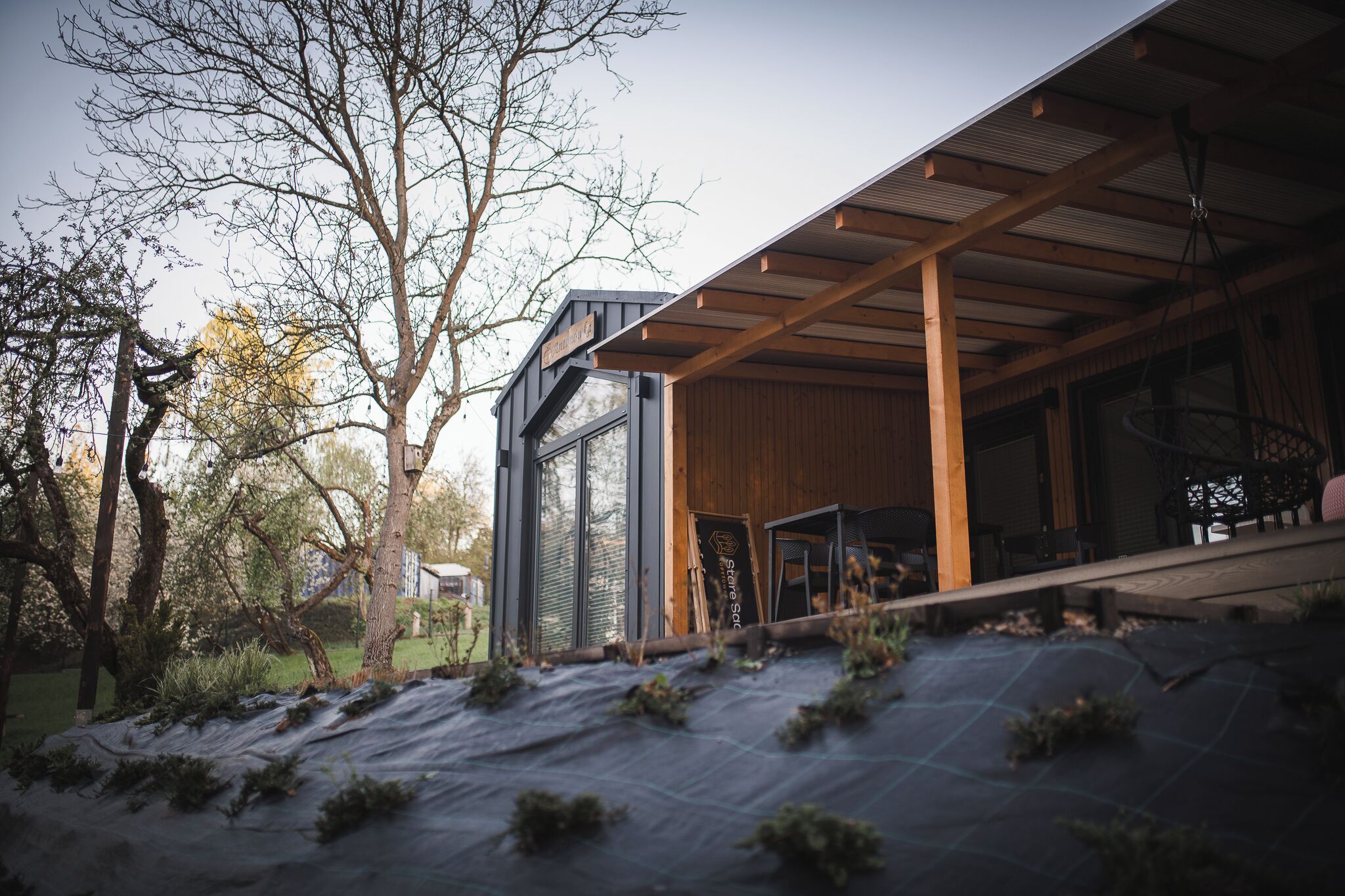 A modern building with a wooden exterior, large windows, and a covered outdoor area.