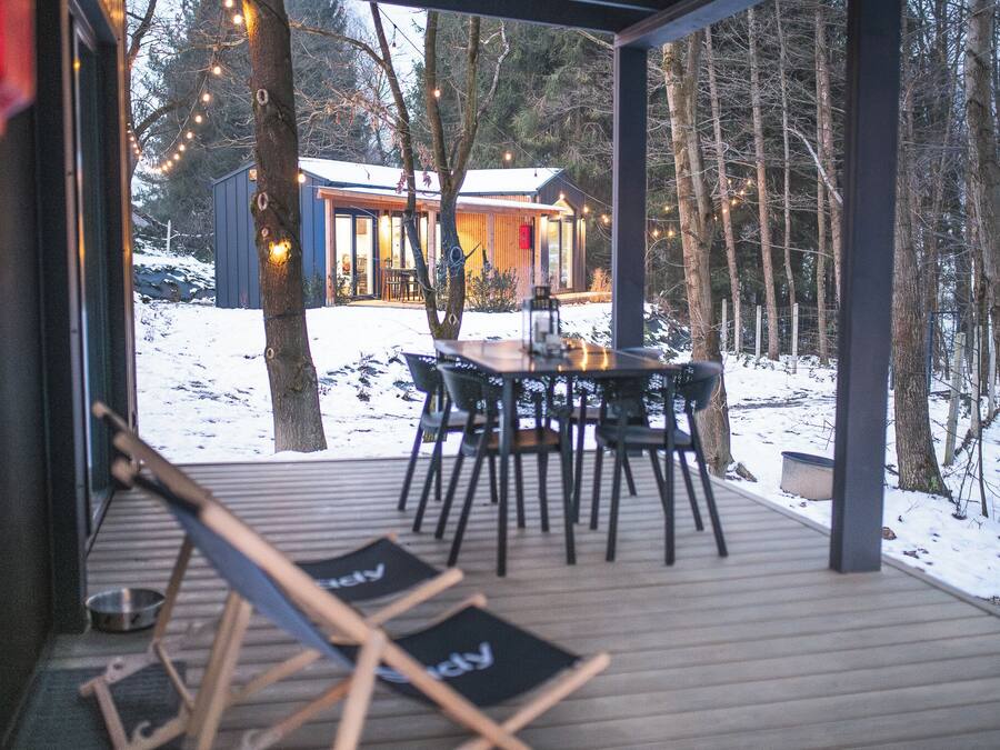 A wooden deck with a table and chairs, a dog bowl, and a dog leash.