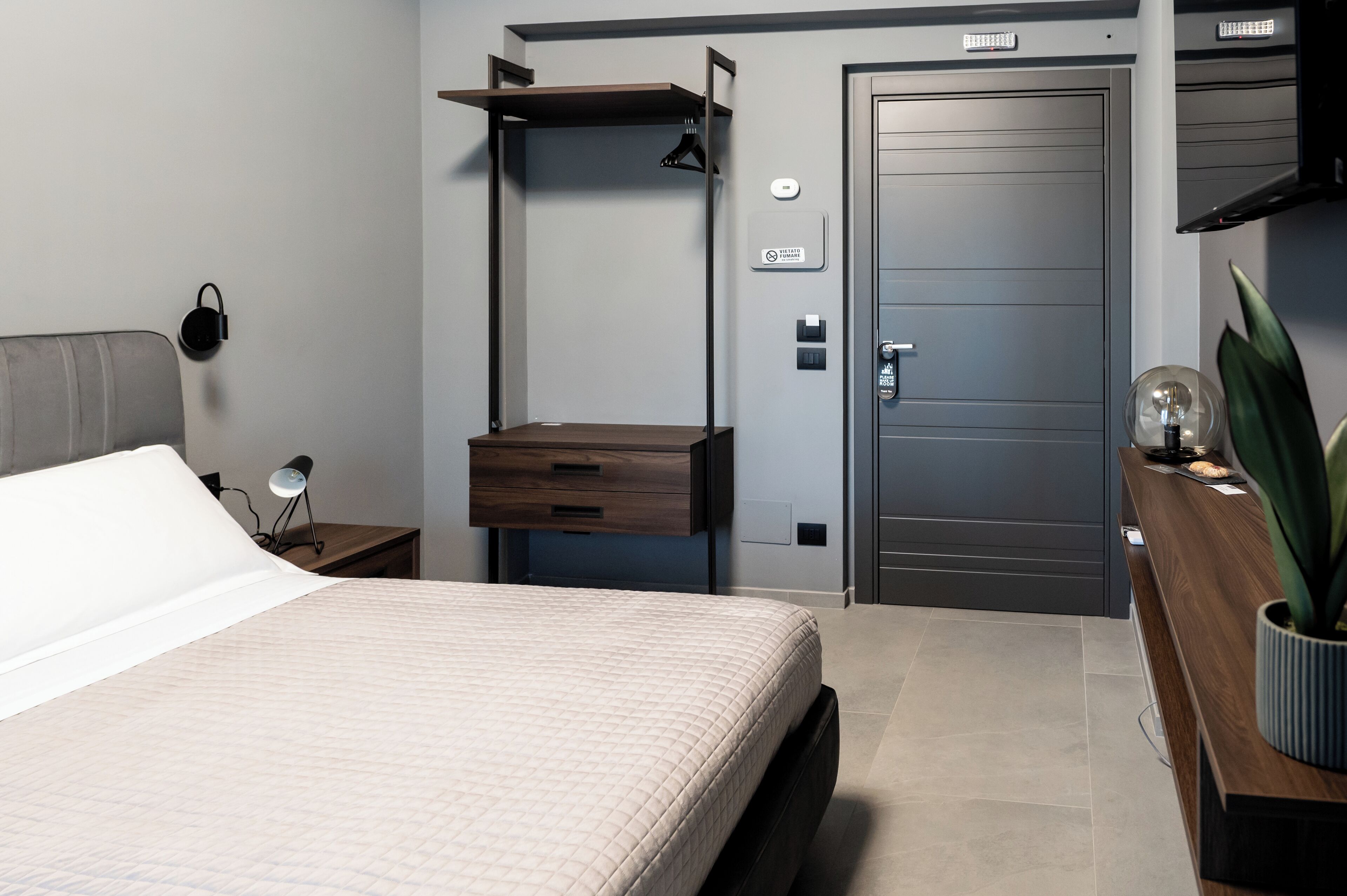 A modern bedroom with a bed, bedside table, lamp, and a built-in shelf.