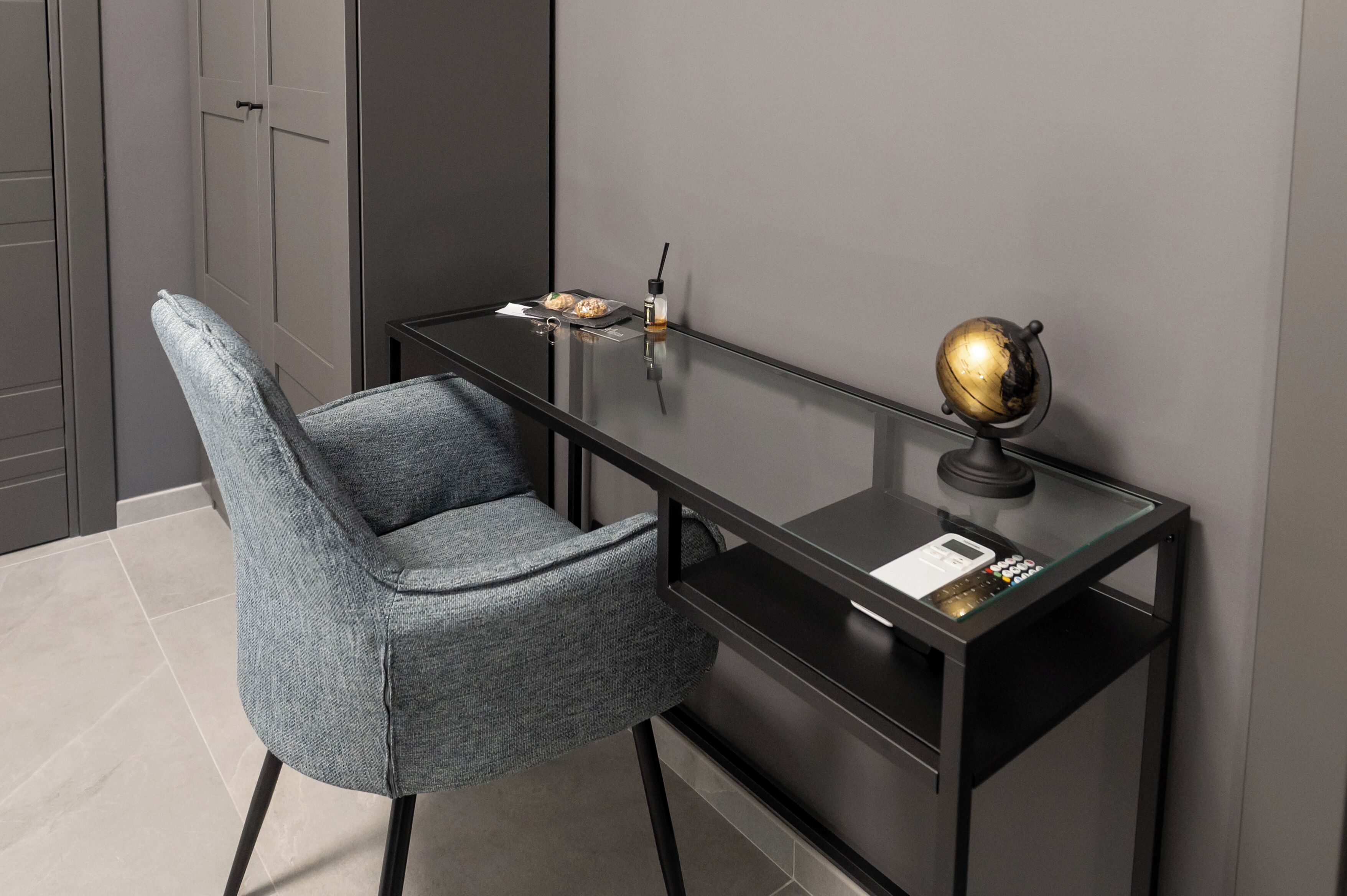 A modern office desk with a chair, a globe, a lamp, and a small table with a tray.