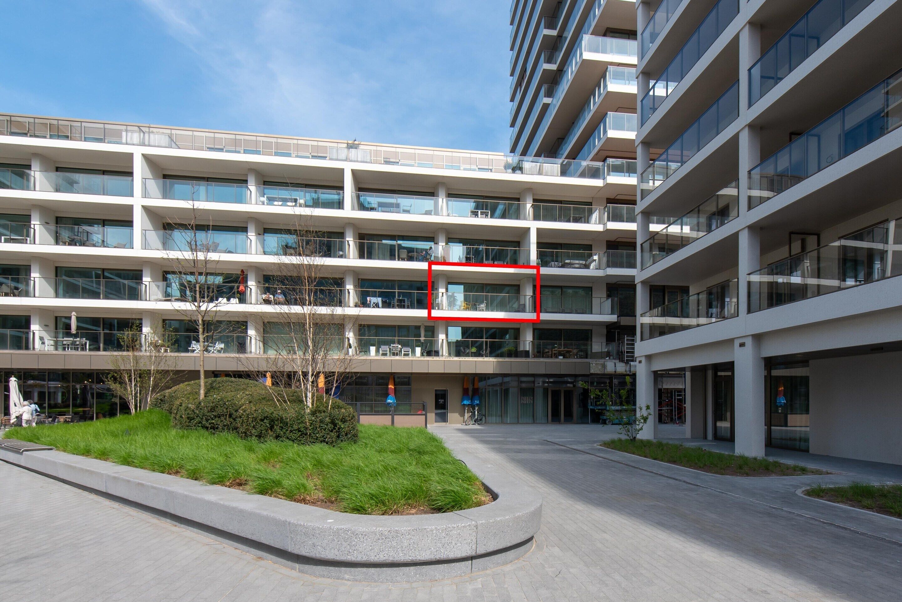 A multi-story building with a modern architectural design, featuring balconies and large windows.