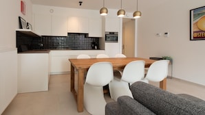 Une cuisine moderne avec des meubles blancs, une table à manger en bois et des chaises blanches.