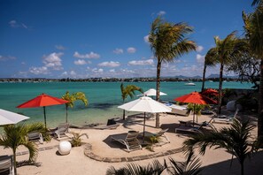 A beachside resort with sun loungers, umbrellas, and palm trees. - Baystone Boutique Hotel & Spa (Grand-Baie)