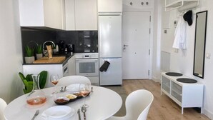 Une cuisine moderne avec des meubles blancs, un plan de travail noir et un coin repas comprenant une table et des chaises blanches.