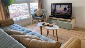Un salon moderne avec un canapé, un téléviseur et une petite table sur laquelle sont posés des verres à vin et des bols.