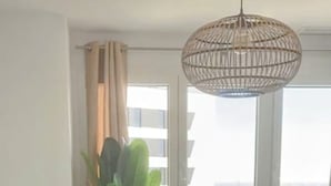 Un salon moderne comprenant un canapé, deux fauteuils, une table basse et une grande fenêtre donnant sur la ville.