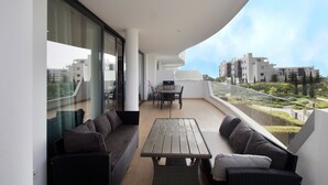 Ein Balkon mit einer Couch, einem Tisch und Stühlen mit Blick auf eine Stadtlandschaft.