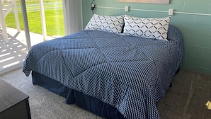 A bedroom with a bed, a view of the outdoors, and a painting on the wall. - Home Near Lake McConaughy (Lewellen)