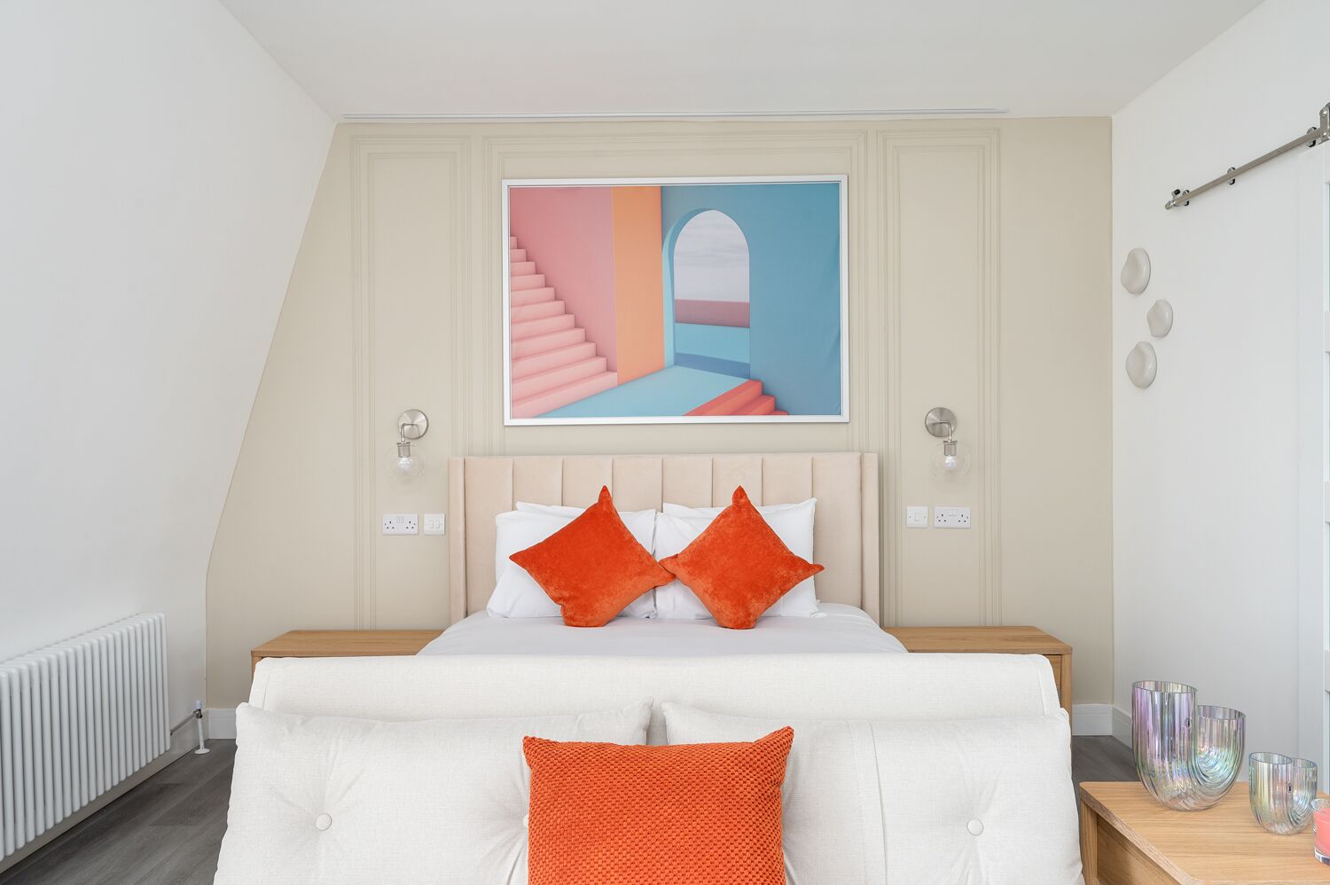 A bedroom with a bed, a painting above the bed, and a nightstand with decorative items.