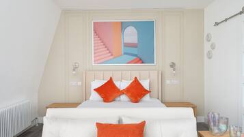 A bedroom with a bed, a painting above the bed, and a nightstand with decorative items.