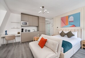 A modern hotel room with a bed, a desk, and a kitchenette. - YTD Residential (London)