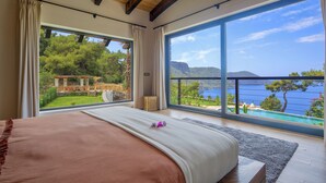 Un dormitorio con un ventanal que ofrece vistas a un jardín exuberante y una masa de agua.