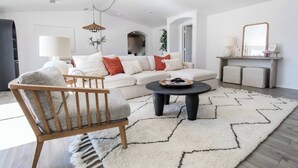 Un salon moderne avec un canapé, une chaise en bois, une table basse et un tapis.