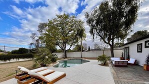 Un jardin avec une piscine, des chaises longues et un espace patio.