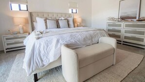Une chambre à coucher avec un grand lit, des tables de chevet, un banc et une commode.