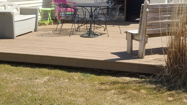 Een gelijkvloers huis met een patio, inclusief een tafel en stoelen, een klein terras en een schuifpui.