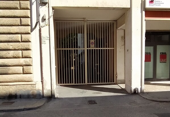 Una entrada con puerta de reja a un edificio, con un cartel que indica una oficina de impuestos CAAF.