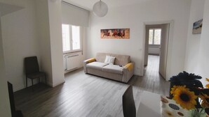 Una sala de estar con un sofá, una silla, un radiador y un cuadro en la pared.