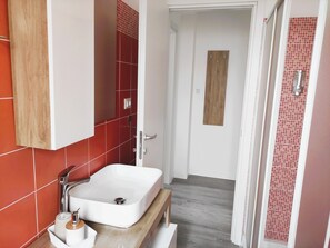 Un baño con un lavamanos blanco, baldosas rojas y una puerta de madera.