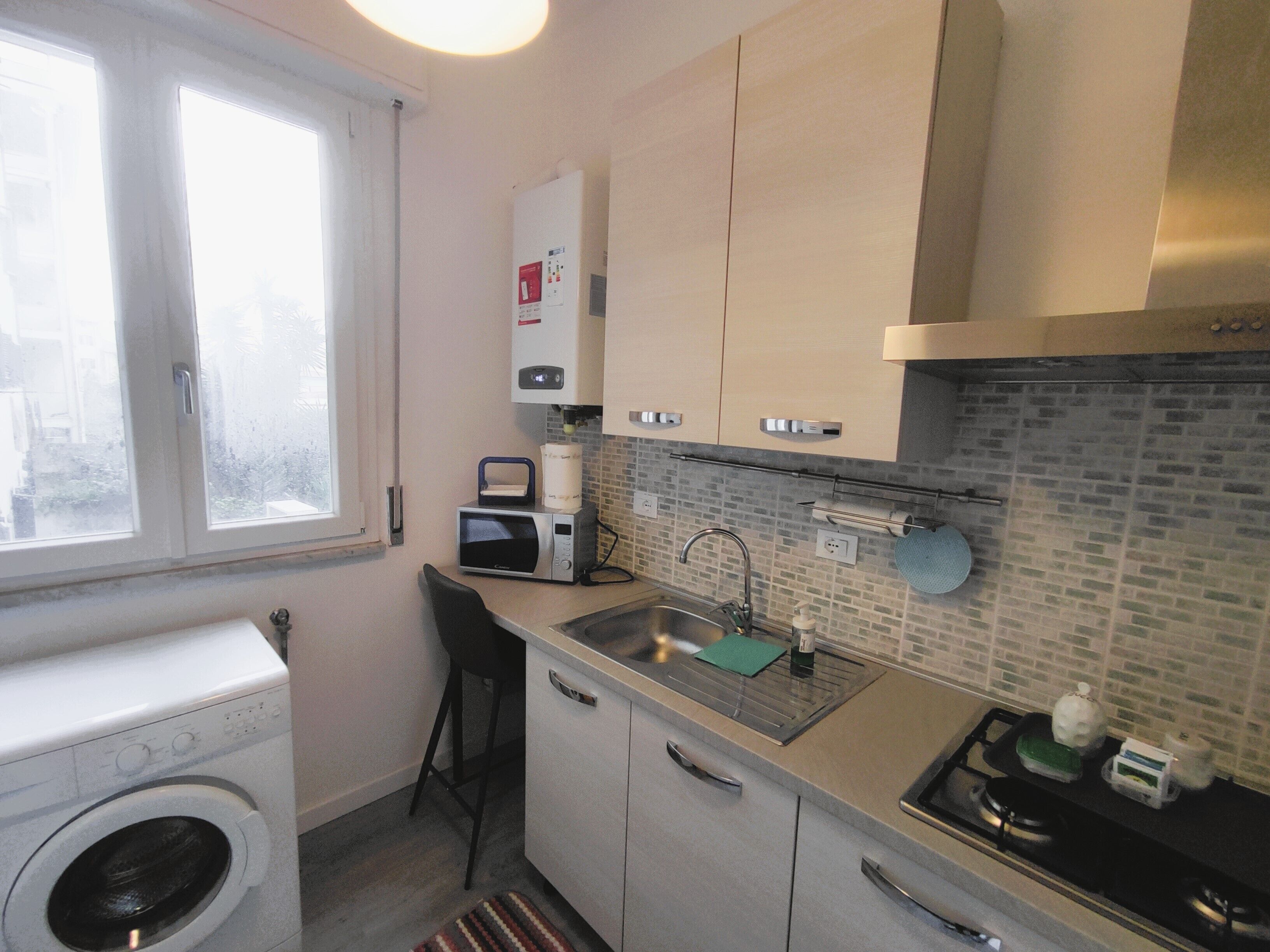 A compact kitchen with a washing machine, a microwave, and a sink.