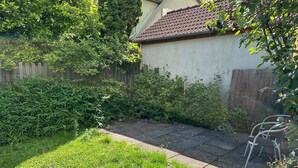 A backyard with a paved patio, a wooden fence, and various plants. - Apartment in the center with garden, connection to Stuttgart, Märklineum and EWS Arena. (Göppingen)