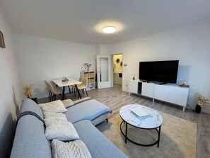 Una sala de estar moderna con sofá, mesa de centro, televisor y comedor.