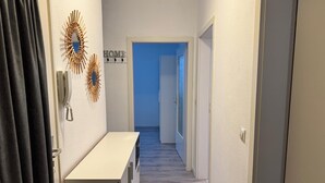 A narrow hallway with a white bench, a wall-mounted telephone, and a decorative sunburst mirror. A 'HOME' sign is visible in the background. - Apartment in the center with garden, connection to Stuttgart, Märklineum and EWS Arena. (Göppingen)