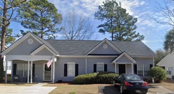 Stunning two-story home with a central entrance, covered porch, and two windows on each side.