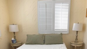 A neatly made bed with a white duvet and a brown skirt, two green pillows, and two bedside tables with lamps. - Spacious 4-bedroom house in enjoyable Dewey Beach with WiFi, AC (Dewey Beach)