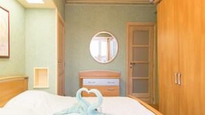 Una habitación de hotel con una cama, un armario de madera, un espejo redondo y una mesita de noche pequeña.