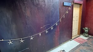 A dark wooden wall with a string of stars, a wooden door, and a small statue. - Mermaid Suite + Private Trails, Cave and Creek! (Topanga)