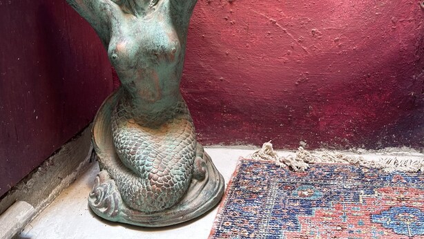 A statue of a woman with raised arms, placed on a patterned rug against a red wall. - Mermaid Suite + Private Trails, Cave and Creek! (Topanga)