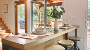 Eine moderne Küche mit einer Holz-Kochinsel, Barhocker und Blick auf die Terrasse.
