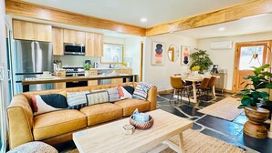 Ein modernes Wohnzimmer mit einer Couch, einem Couchtisch und einem Essbereich mit Stühlen.