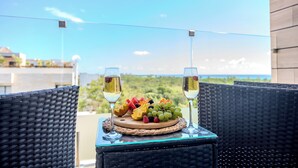 A wicker table with a fruit platter and two glasses of white wine, overlooking a scenic view. - Sea Tower by Casago (Playa del Carmen)