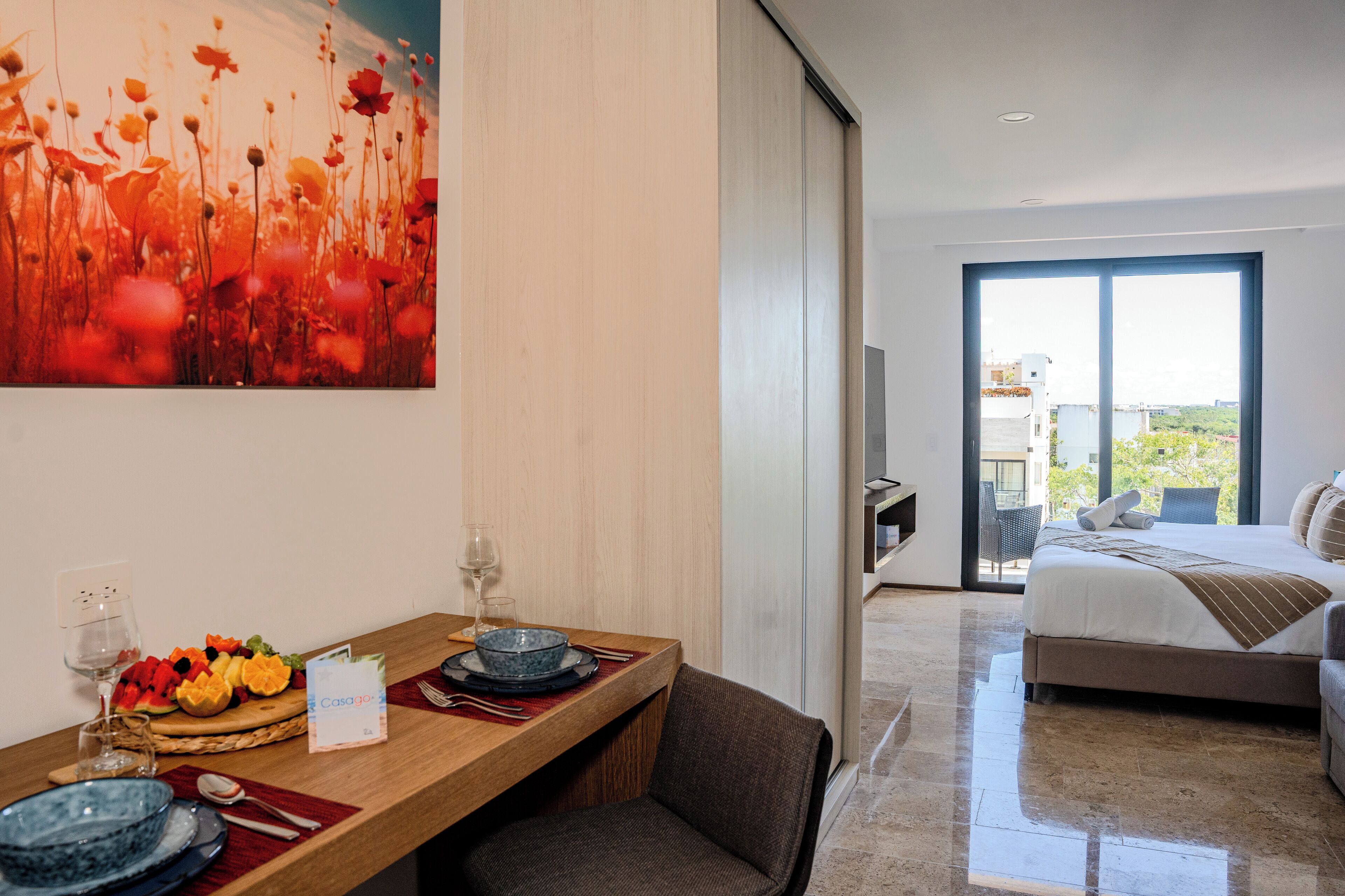Een hotelkamer met een eethoek, een bed en een balkon met uitzicht.