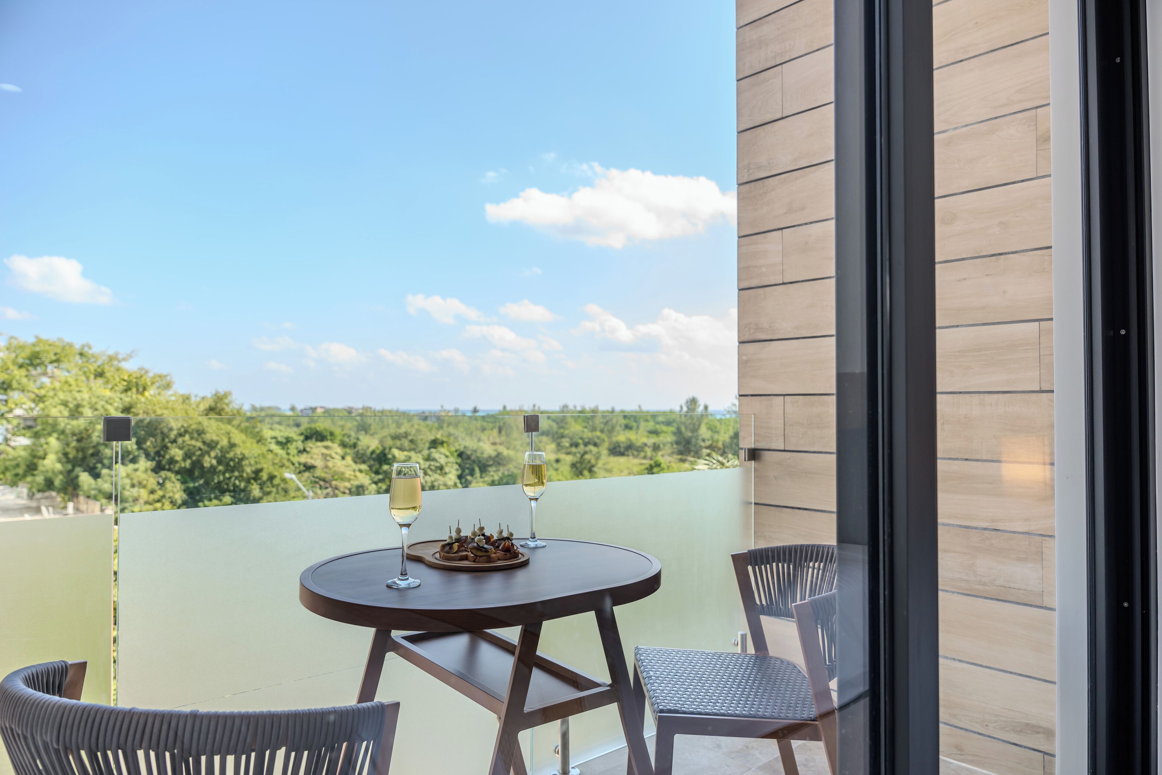A balcony with a round table, two chairs, and two glasses of wine.