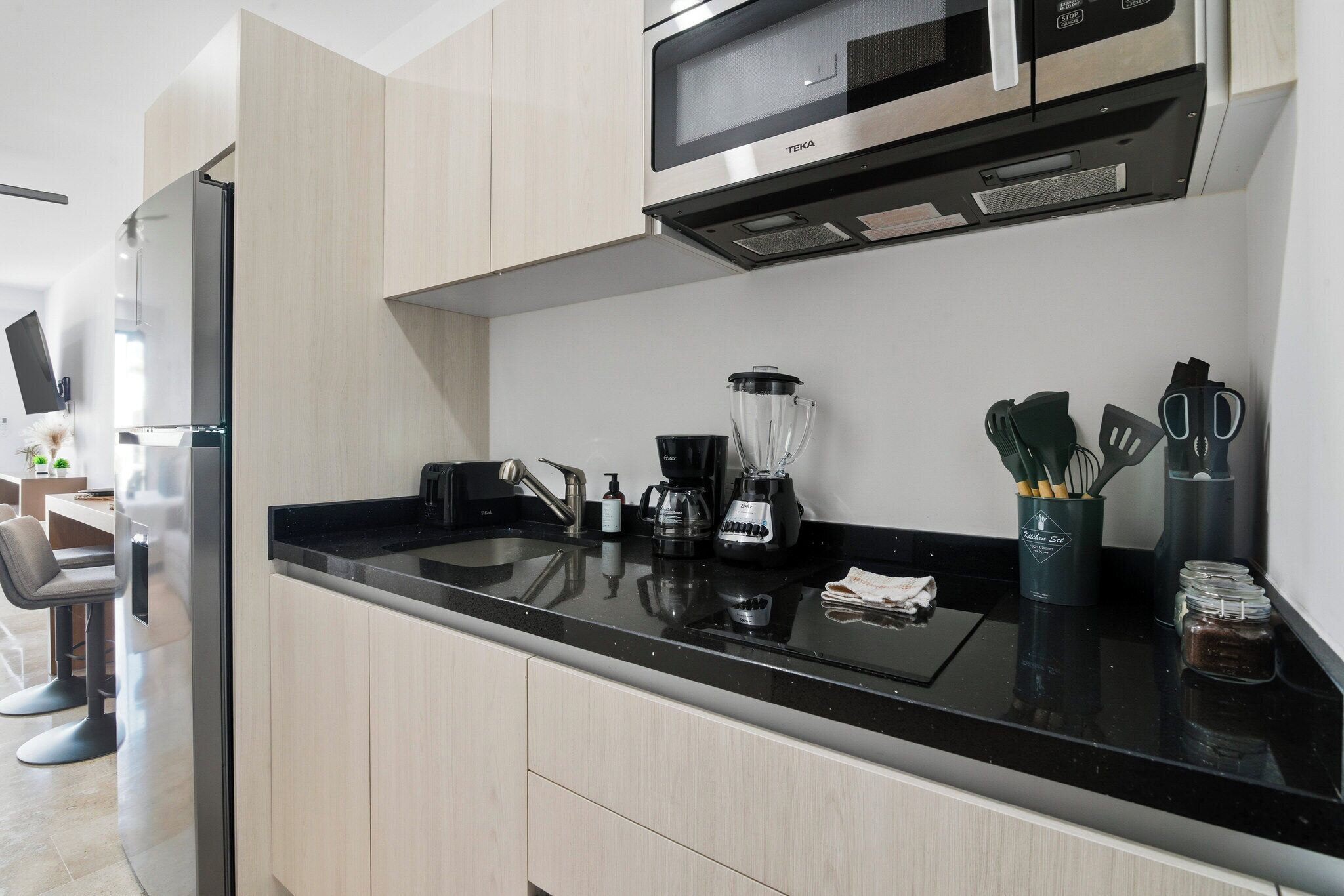 A modern kitchen with a black countertop, stainless steel appliances, and wooden cabinets.