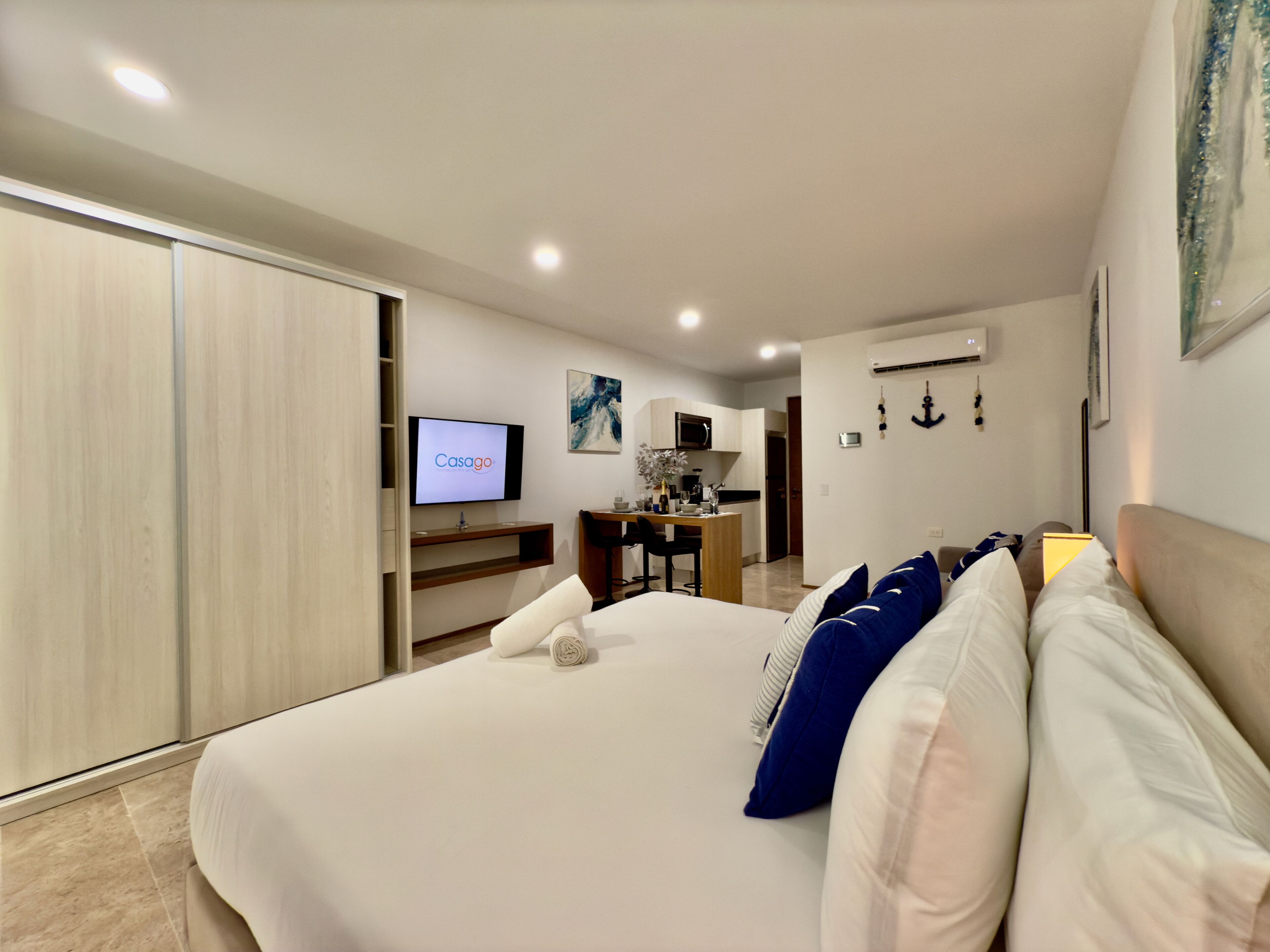 Ein Hotelzimmer mit Bett, Schreibtisch, Fernseher und einer Küchenzeile.