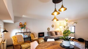 A cozy living room with a fireplace, a round wooden dining table, and a sofa.